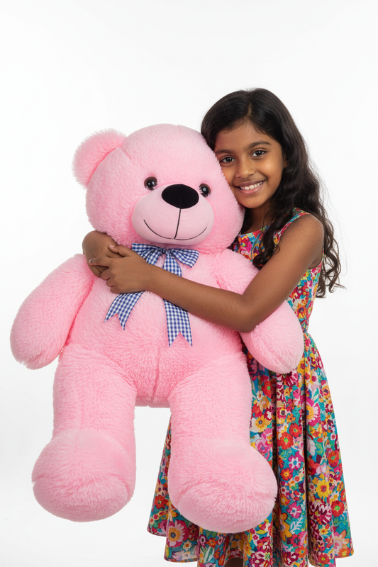 Sri Lankan girl hugging a large pink teddy bear with blue checkered bow tie in studio setting